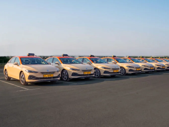Row of MG8 PHEV taxis in beige and orange livery, part of MG's 570-vehicle taxi deployment